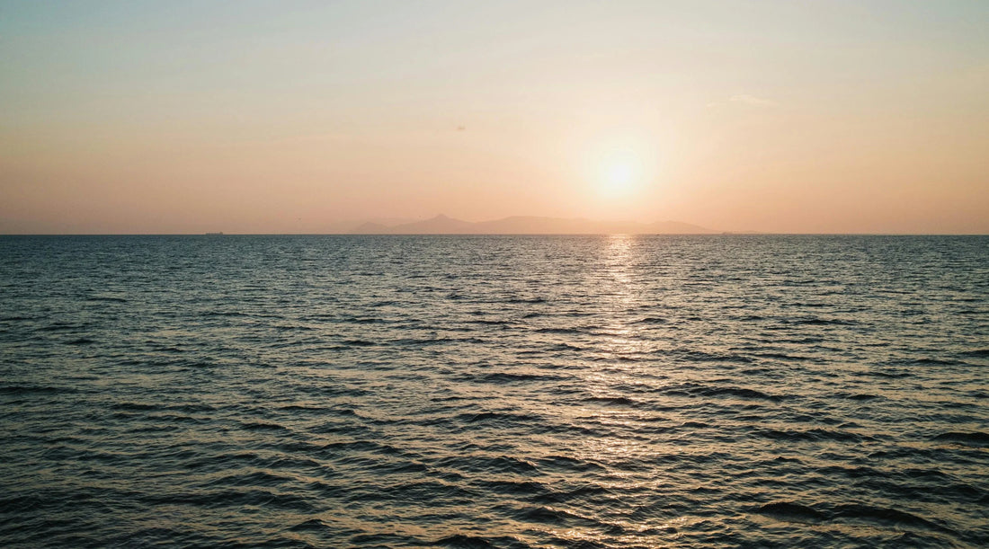 Golden sunset over a calm ocean horizon, reflecting rest, balance, and gentle summer wellbeing, symbolising a slow, steady approach to seasonal health and mindful living.