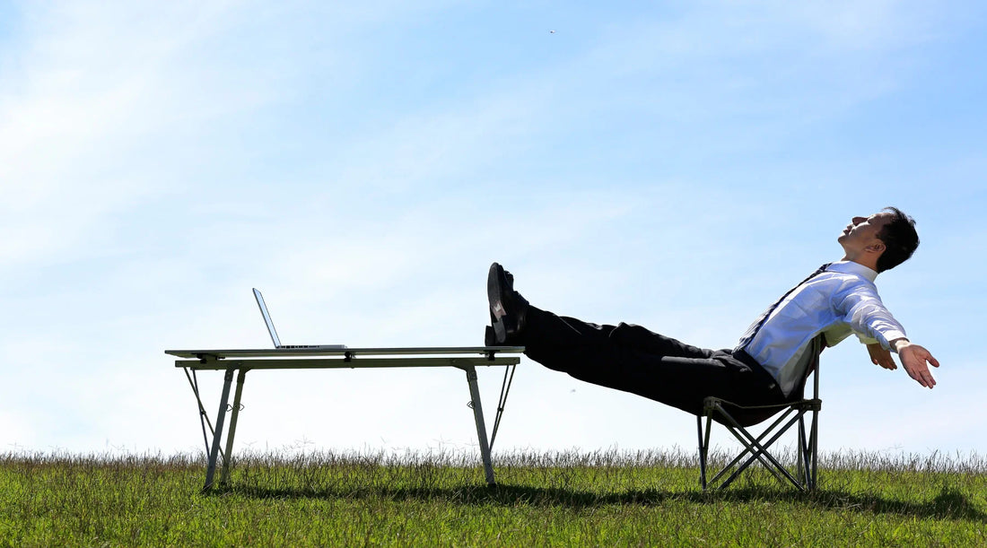 A relaxed man sitting outdoors with his feet up on a desk and laptop in front of him, enjoying fresh air and calm surroundings symbolising renewal, balance, and the freedom that comes with a spring detox and natural reset.