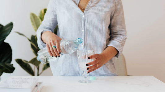 Person pouring water into a glass at home, representing daily hydration habits that support energy, digestion, and overall wellbeing, especially during warmer months.