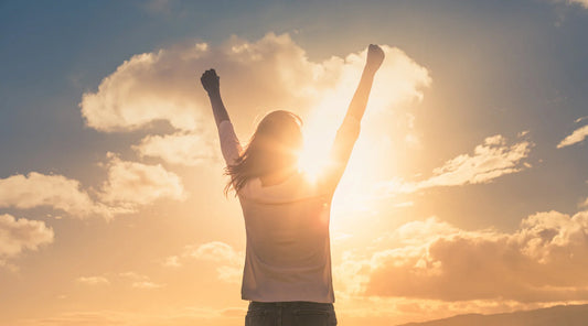 Woman raising arms towards the sunrise, symbolising vitality and the natural immune support benefits of NAC and Quercetin.
