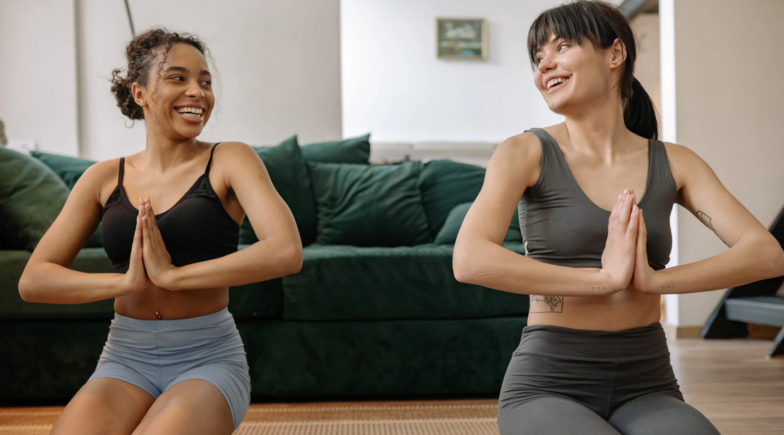 Two women practising yoga together at home, supporting women’s health, movement, mental wellbeing and everyday wellness.