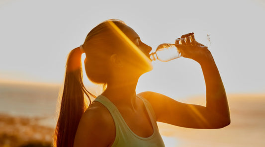 Woman drinking water outdoors in warm weather as part of healthy spring hydration habits in Australia.